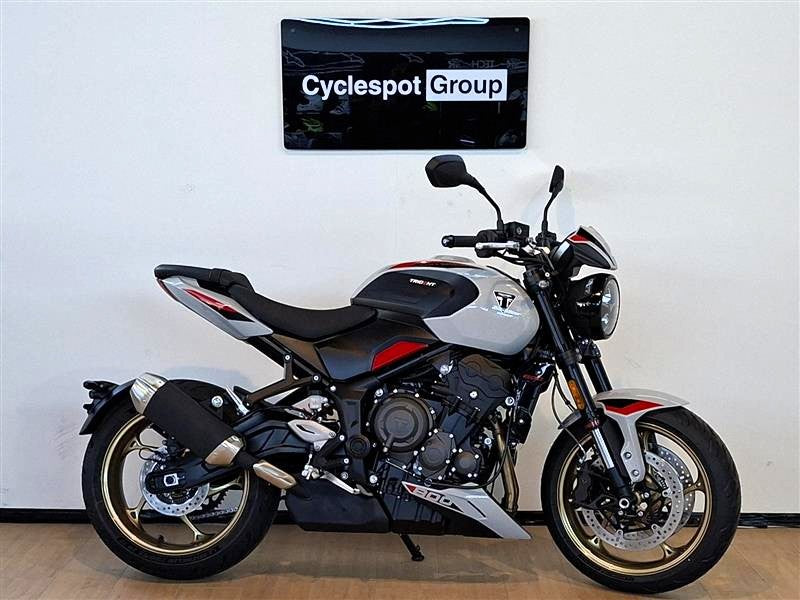 Load image into Gallery viewer, A silver and black Triumph Trident 800 motorcycle with red accents, parked indoors against a white wall with a 'Cyclespot Group' sign above it.