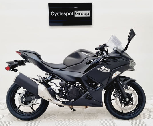 Black Kawasaki Ninja 500 motorcycle on a white floor with 'Cyclespot Group' sign in the background