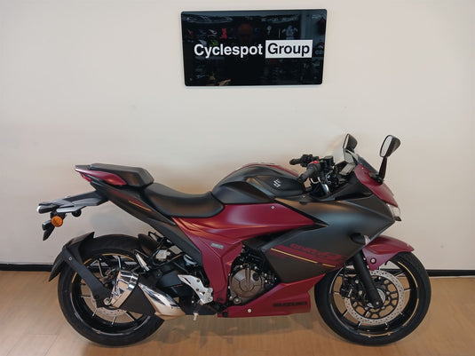 Crimson red and black 2025 Suzuki GSX 250 FR motorcycle on display with 'Cyclespot Group' branding in the background