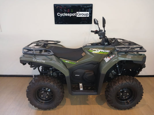Green CF Moto C-Force 400 non-eps model on a wooden floor in front of a Cyclespot Group sign