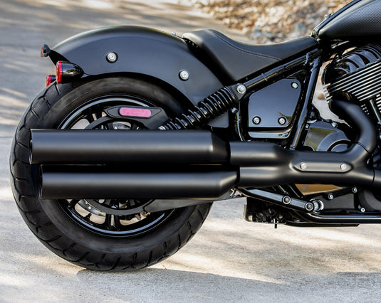 Close-up of a black 2026 Indian Chief Dark Horse cruiser motorcycle showing the rear wheel, dual exhaust pipes, fender, and side bodywork on an outdoor paved surface.