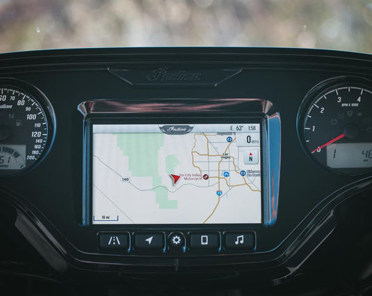 A close-up of a 2026 Indian Roadmaster Dark Horse dashboard display screen showing a navigation map, framed by instrument gauges and a black console with a visible Indian logo above.