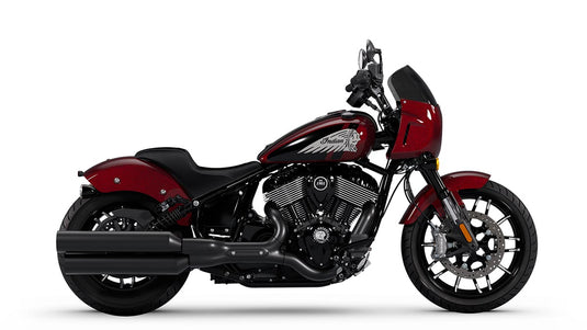 A side profile view of a cruiser motorcycle, specifically an Indian Sport Chief, in a deep metallic red and black color scheme, set against a plain white studio background.